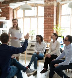 Ambitious employee raise hand ask question to presenter at meeting, teambuilding with multiethnic colleagues, diverse workers brainstorm at office education briefing